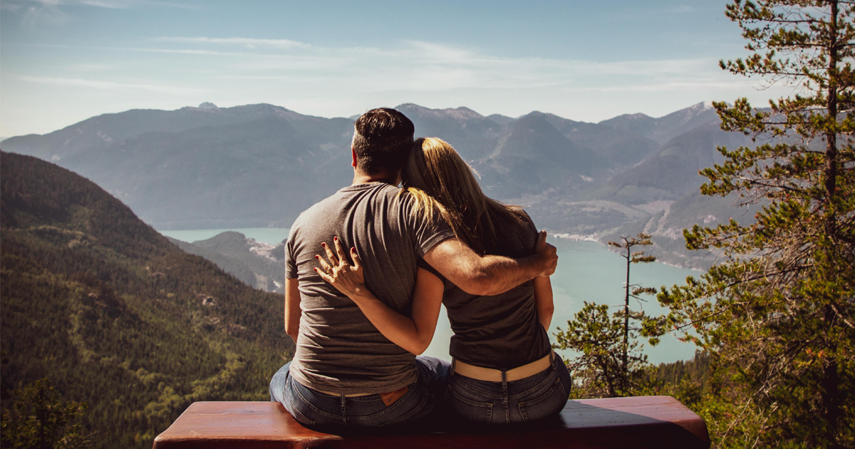 Couple embracing while overlooking mountain lake view