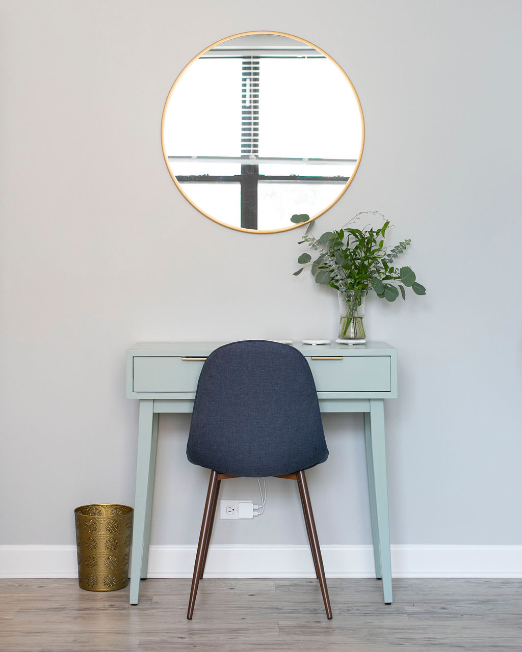 Desk with wall mirror, wastebasket, and potted plant