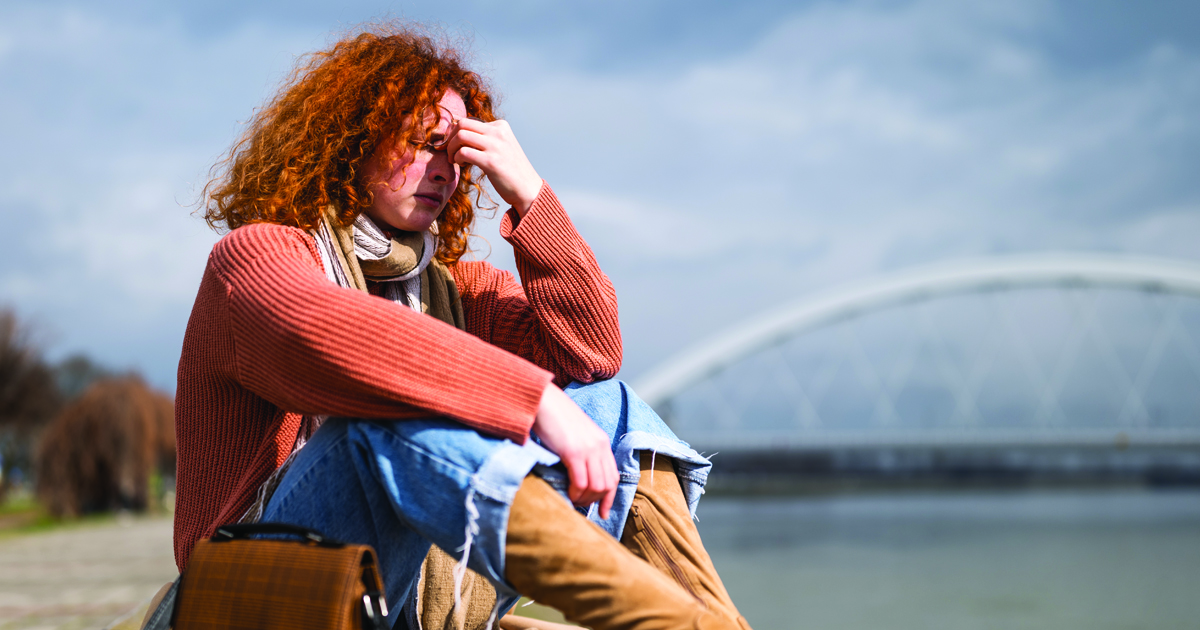 Person leaning forward with hand on face, showing signs of exhaustion