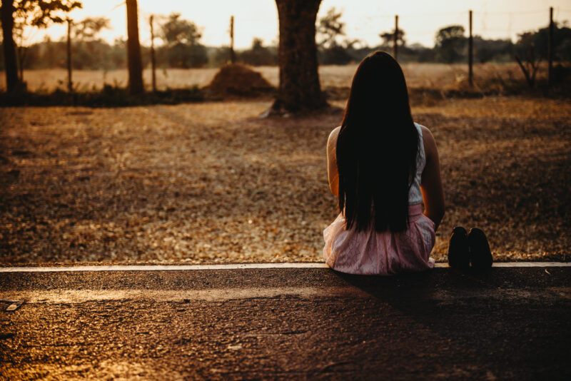 Woman Sitting Contemplatively Outdoors at Sunset