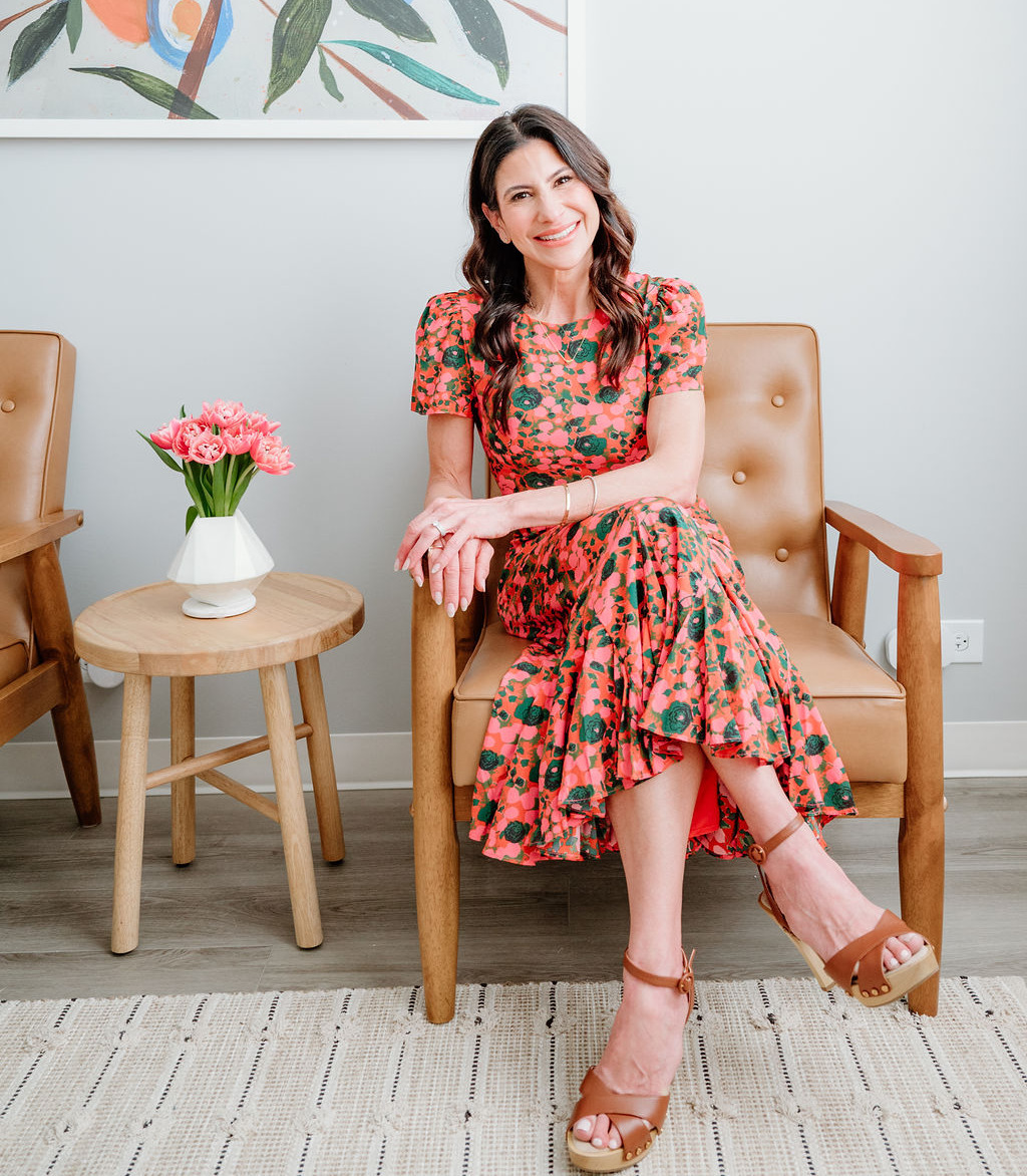 Nicolle Osequeda, M.A., M.Ed., MFT, founder of Lincoln Park Therapy Group, smiling in a leather armchair